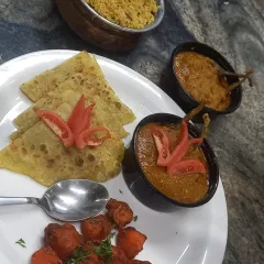 A complete and balanced North Indian meal, featuring soft parathas, a rich gravy, a dry vegetable side, and dal. This represents the wholesome and tasty daily lunch options we can provide for your team.