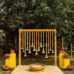 This outdoor Haldi ceremony setup is perfect for a garden or lawn event. The simple wooden frame is decorated with hanging strings of bright yellow marigolds, creating a beautiful and auspicious space for the ritual.