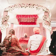 A serene moment from a Sikh wedding, showing the couple during the Anand Karaj ceremony from a respectful distance, with the beautiful mandap in the background.