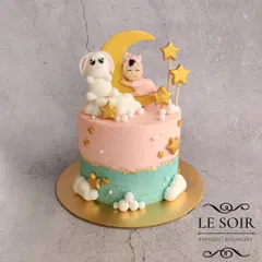 A sweet and dreamy cake for a baby shower. This 1 kg Chocolate Truffle cake features a soft pink and teal color palette, with a baby sleeping on the moon, a bunny, and golden stars.