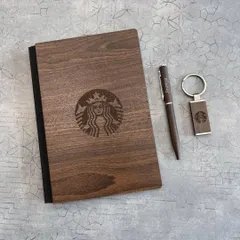 I can engrave intricate logos onto wooden surfaces, as shown with this Starbucks set. The laser engraving on the dark wood diary, pen, and keychain creates a premium, rustic feel.