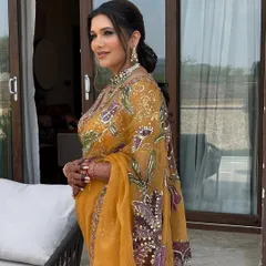 A beautiful braided ponytail on a client wearing a stunning yellow saree. The hair is braided at the top and flows into a messy, textured ponytail, creating a look that is both traditional and modern.