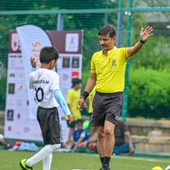 A young player respectfully interacts with a KSFA official referee. I ensure all my youth league matches are officiated professionally to teach the importance of rules and respect from a young age.