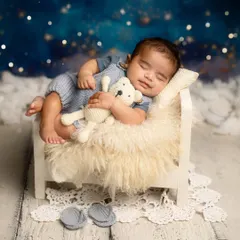 Dreaming among the stars. This setup features a tiny bed, a cuddly teddy bear, and a magical night sky backdrop for a truly dreamy portrait.