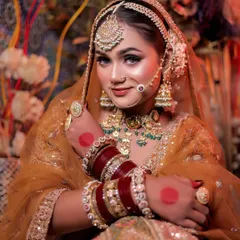 A smiling portrait of the bride, her hands adorned with alta, showcasing her traditional bangles and jewelry.