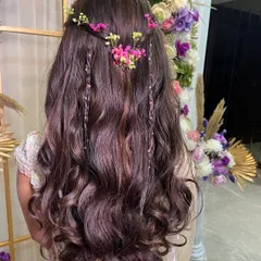 A whimsical and romantic hairstyle for a mehendi or sangeet. Soft waves are interwoven with delicate braids and fresh baby's breath, creating a bohemian-chic look.