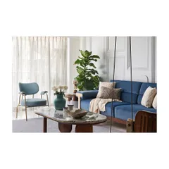 The living room features a soothing color palette with a plush blue sofa and a custom lounge chair. The space is designed to feel relaxed and structured, with classical wall mouldings adding a touch of elegance.