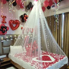 A first-anniversary room decoration with a personal touch. Along with the light canopy and rose petals, I've added a string of photos above the headboard to make the celebration even more special.