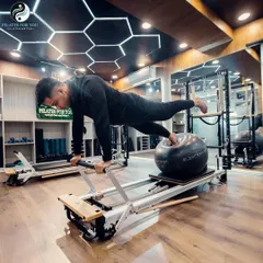 Performance Pilates isn't just about flexibility. This single-leg high plank on the reformer, combined with a stability ball, is an advanced exercise for building immense core strength and balance.