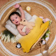 Wide-eyed and full of wonder. This newborn is awake and alert, looking so cozy in a yellow blanket with a tiny teddy bear.
