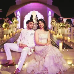 The couple, dressed in coordinated white and pastel outfits, poses against the stunning backdrop of their rooftop Sufi Night, surrounded by hundreds of candles.