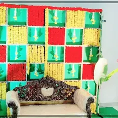 A colorful chequered backdrop created with panels of red fabric and yellow marigolds, accented with banana leaves. This vibrant and traditional setup is ideal for a variety of pre-wedding functions.