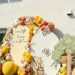 Our classic Winnie the Pooh baby shower theme, "Our Little Hunny is on the way". This outdoor setup brings the Hundred Acre Wood to life with custom character cutouts, themed backdrops, and a cheerful balloon arch in shades of yellow, orange, and cream.