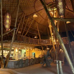 The intricate construction and warm lighting of this multi-story bamboo building in Bali showcase a mastery of sustainable architecture.