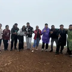 A happy group giving thumbs up at the summit, celebrating their successful trek together.