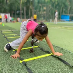 Agility ladder drills are a staple at our active birthday parties. Here, a young girl focuses on her footwork, navigating the ladder with speed and precision in a fun, game-like setting.