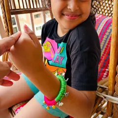 I designed this jingly bangle especially for kids. It's a wooden base wrapped in bright satin ribbon, with tiny golden ghungroos and little haathi charms that make a happy sound with every movement.