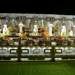 This expansive fruit and dessert station is designed to be a showstopper. The elegant white and gold counter is laden with fresh fruits and a variety of sweets, all under bright, focused lighting.