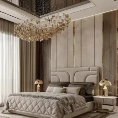 This luxury bedroom combines a quilted bed, a stunning crystal chandelier, and a soft, neutral color palette with gold trim for a warm and inviting feel.