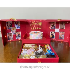 A full view of my Raksha Bandhan Special Gift Hamper Box. You can see the custom cake, the photo-lined walls lit by fairy lights, and the drawer below filled with chocolates, brownies, and a Rakhi.