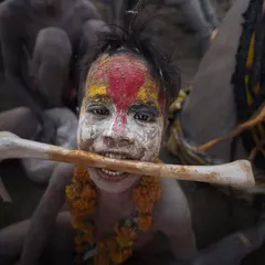 A child participant in Masan Holi, smiling with a bone in his mouth. The image is both startling and endearing, capturing the innocence within a formidable tradition.