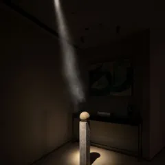 A single, powerful beam of light acts as a sculptural element itself, illuminating a stone artifact on a plinth. This demonstrates our belief that great design is not just seen, but felt.