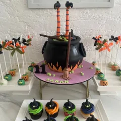 A spooky and spectacular witch's cauldron cake for a Halloween party. This custom cake features a bubbling cauldron with a witch's legs sticking out, and was part of a dessert table with themed cupcakes and pumpkin cakepops.