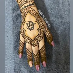 A unique logo-themed mehendi for an engagement. Using the couple's initials to create a custom monogram is a modern and sophisticated way to personalize your henna.