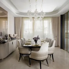 A gathering in grace. We designed this dining space for shared meals and stolen moments, under a canopy of crystal blooms. The neutral palette of the chairs and walls creates a calm, elegant atmosphere.