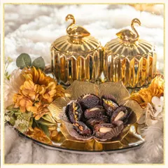 This stunning gold-themed hamper is perfect for Eid celebrations. It features ornate swan-topped jars and a floral bowl filled with almond-stuffed dates, all on a mirrored tray.