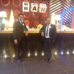 Two of our lead butlers in formal attire, standing proudly in front of a bar they've set up. We provide the best service to make your function enjoyable.