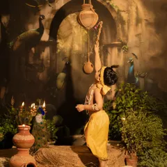 A dynamic shot of the boy as Krishna, playfully reaching for a hanging pot of butter (makhan). This action pose brings the mischievous and beloved stories of Lord Krishna to life.