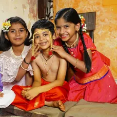 A heartwarming group photo of children during a 'Munj' or thread ceremony. The playful interaction between the young boy in his traditional attire and the girls creates a lively and memorable family moment.