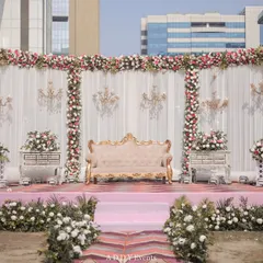 We created this royal-themed outdoor stage with a backdrop of white drapes, floral borders, and hanging crystal chandeliers. The blush pink stage and vintage-style sofa add a touch of softness and romance to the grand design.