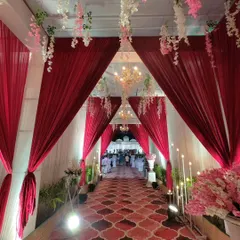 Another perspective of the red draped entrance, showing how the layers of fabric and hanging flowers create depth and a sense of procession for guests as they walk towards the main event area.