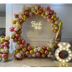 Let the bachelorette party begin! This circular balloon arch in white, gold, and pink, complete with a "Bride to be" neon sign and a light-up diamond ring prop, is perfect for those fun-filled photo sessions.