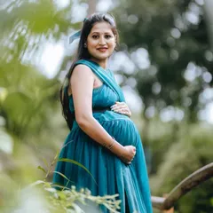 The rich teal color of this maternity gown looks stunning in natural light. Its simple, elegant design with a wraparound top is perfect for highlighting the baby bump in a comfortable and stylish way.