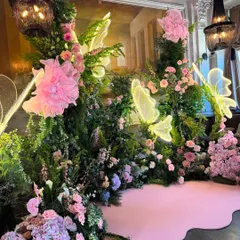 For an intimate gathering, we created this enchanting floral backdrop. A dense arrangement of pink flowers and greenery is accented with glowing neon butterfly lights, creating a magical and romantic photo space.
