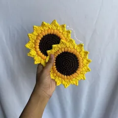 A clear product shot of two crochet sunflower coasters against a white background. This highlights the clean stitching and bright, cheerful design.