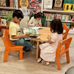 Friends reading together. Our club is a place for kids to connect with others who share their love for stories, sitting around a table and getting lost in different worlds.