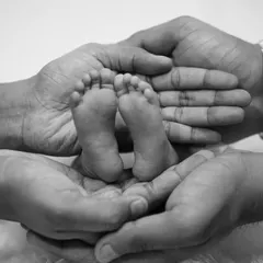 The tiniest feet make the biggest footprints in our hearts. This classic black and white shot of a newborn's feet held in their parents' hands is a timeless keepsake.