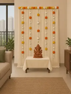 An illustration of what about ₹5,000 buys: a plain cream cloth backdrop behind the idol, hung with strings of orange, yellow and white artificial flowers and edged along the top with the same flowers, and a small clay Ganesha on the family's own low table in front