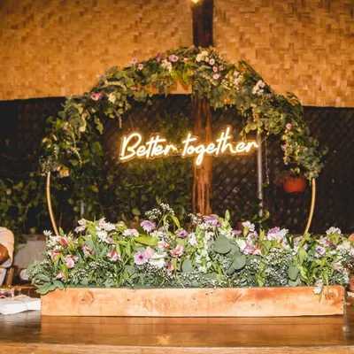This 'Better Together' neon sign served as the centerpiece for a rustic-themed anniversary backdrop. I combined it with a circular metal arch adorned with lush greenery and wildflowers to create a modern yet natural look for the couple's celebration.