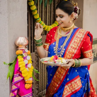Celebrating the Maharashtrian new year with a traditional Gudi Padwa shoot. This image captures the model performing the puja, dressed in a stunning blue and red Paithani saree, surrounded by festive decorations.