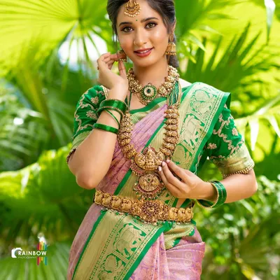 A beautiful bridal look featuring a classic Kanjivaram saree. The vibrant green and pink are set against a natural green background, making the temple jewellery and the fabric's gold zari work stand out.