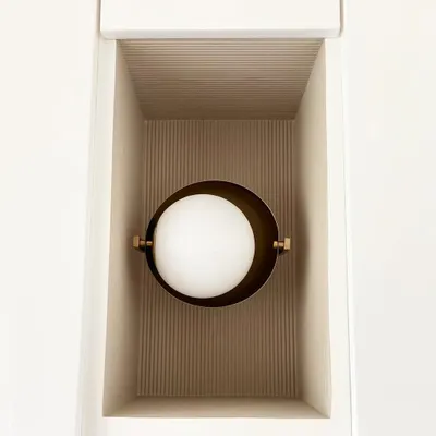 A simple niche transformed into a design feature. The fluted texture inside the niche catches the light beautifully, highlighting the modern, globe-shaped brass sconce.