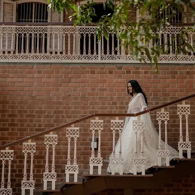 A vision in white. This bride's elegant Tarun Tahiliani lehenga looks absolutely stunning against the rustic brick backdrop, creating a timeless and regal bridal portrait.