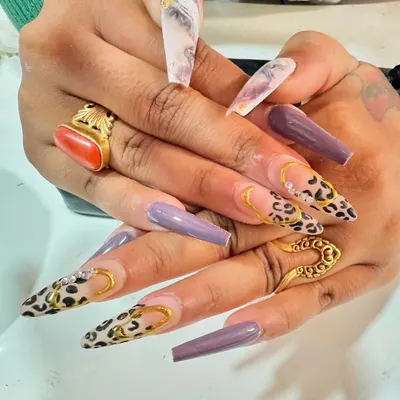 Go bold with these dramatic long nails. This set features a fierce combination of solid purple, marble, and a classic cheetah print with 3D gold chain details.