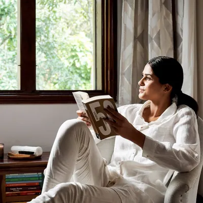 A guest finds a peaceful moment to read by the window, with natural light streaming in and the lush greenery of our garden just outside. This is the essence of unwinding at Ayurvedagram.