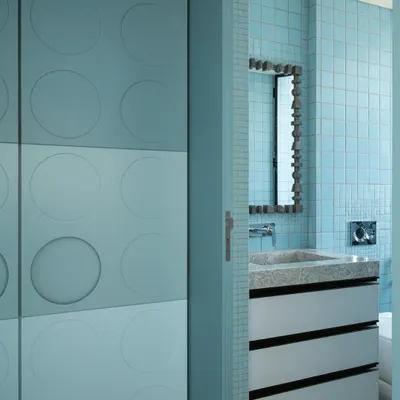 A glimpse into a bathroom designed for one of the sons in a family home. The space features a custom stone vanity with clean lines, paired with a playful circular-motif wardrobe just outside, blending sophistication with a touch of whimsy.